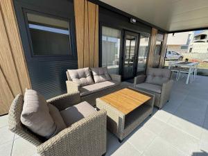 a patio with wicker chairs and a table and a television at Ljubac Harmony Mobilház in Ljubač