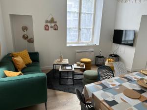 a living room with a green couch and a table at L'Annexe du Cloître in Toul