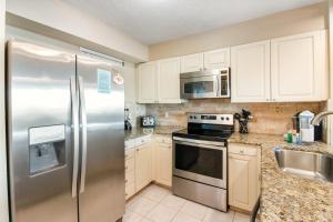 a kitchen with white cabinets and a stainless steel refrigerator at Magnolia House at Destin Pointe 203 in Destin