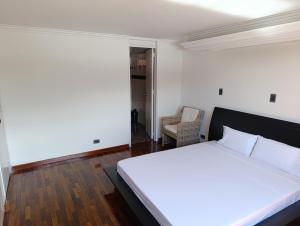 Un dormitorio con una cama blanca y una silla. en De vuelta al sol, en Medellín