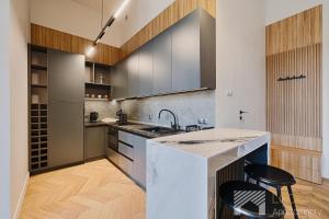 a kitchen with a sink and a counter with two stools at Jaracza Exclusive by LookAp - darmowy parking w centrum!! in Łódź