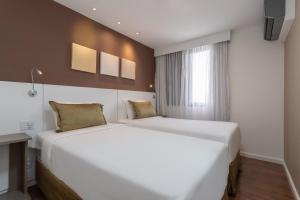 two white beds in a room with a window at Paulista Suítes by Charlie in São Paulo +18 photos