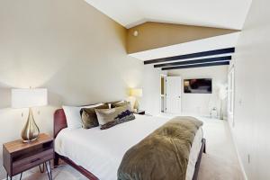 a bedroom with a large white bed and a table at Booth Falls Chalet in Mid Vail
