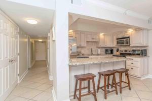 Ono IslandにあるSea Spray 505Wの白いキャビネットとバースツール2つ付きのキッチン