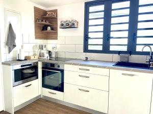 a kitchen with white cabinets and a sink at La Kazadoo in Piton Saint-Leu +5 photos