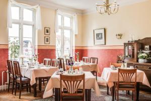 a dining room with tables and chairs and a chandelier at Hotel Klein Amsterdam in Friedrichstadt