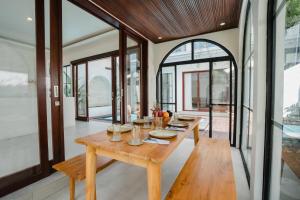 a dining room with a wooden table and large windows at Honey Villa Canggu in Canggu