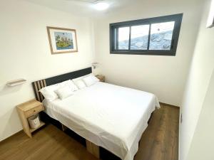 a bedroom with a white bed with a window at La Kazadoo in Piton Saint-Leu