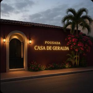 a sign on the side of a building with a palm tree at Pousada Casa de Geralda in Altaneira