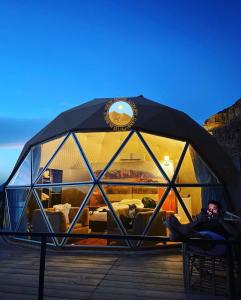 a man is sitting in a glass igloo at RUM BUBBLES VIEW MARS lUXURY CAMP in Wadi Rum