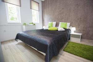 1 dormitorio con 1 cama grande con almohadas verdes en Cozy Apartment, en Hajdúszoboszló