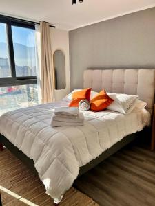 a bedroom with a large bed with orange and white pillows at Depto moderno en Nuñoa cerca Metro y Barrio Italia in Santiago