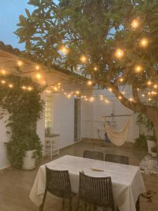 un patio con una mesa y un árbol con luces en Un pequeño lujo a pocos metros de la playa, en Piles