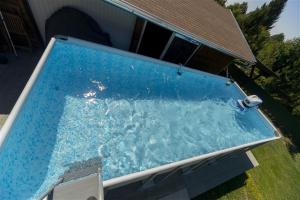 a large blue swimming pool in front of a house at Tornácos Vendégház in Salgótarján