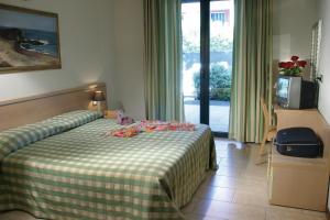 una camera d'albergo con un letto con una coperta verde e bianca di Residence Spiaggia D'Oro a Desenzano del Garda