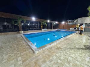 a swimming pool at night with people standing around it at Sensacional Flat pé na areia na Praia da Costa in Vila Velha +7 photos