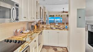 a kitchen with white cabinets and marble counter tops at Kapalua Bay Villa 35B2 in Kapalua