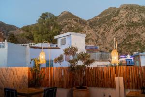 a house with a fence and mountains in the background at Riad Tassili Chaouen in Chefchaouene