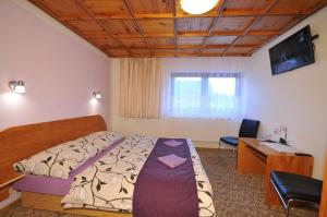 a bedroom with a bed and a desk and a computer at Penzión U Aleny in Ždiar