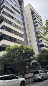 due auto parcheggiate di fronte a un palazzo alto di Apartamento moderno a 2 quadras da Praia da Costa - completo, espaçoso e com mimo especial a Vila Velha