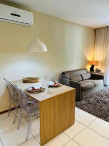 a living room with a table with chairs and a couch at Iloa resort AP luxo in Barra de São Miguel