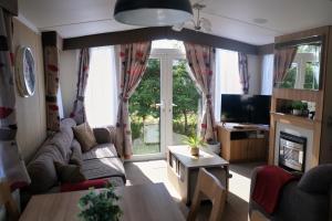 a living room with a couch and a tv at 64 Southfield - Skipsea Sands in Ulrome