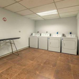 a laundry room with four washing machines and a table at Hostal PdeV in Concepción