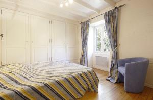 a bedroom with a bed and a chair and a window at Bastide piscine, pétanque, salle de jeux et spa in Guiche