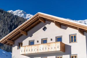 a house with a balcony with mountains in the background at Chalet Silver Fox in Sankt Anton am Arlberg