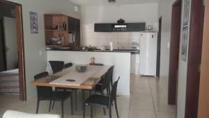 a kitchen with a table and chairs and a kitchen with a refrigerator at Casa de praia-Barra de são Miguel in Barra de São Miguel