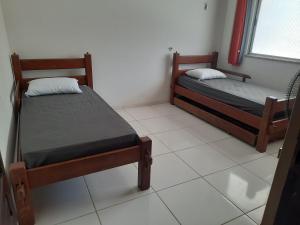 two beds in a room with a white tile floor at Ilha do Mosqueiro Família in Belém