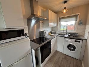 a kitchen with a sink and a washing machine at 58, Two bed chalet on Sund0wner Holiday Park - Sleeps 4, pet friendly - Free WiFi plus electricity all included - Entertainment options close by in Hemsby