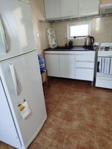 a kitchen with a white refrigerator and a stove at La Torre Departamento in Caleta Olivia