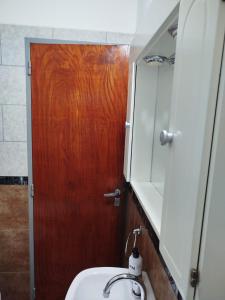 a bathroom with a sink and a wooden door at La Torre Departamento in Caleta Olivia
