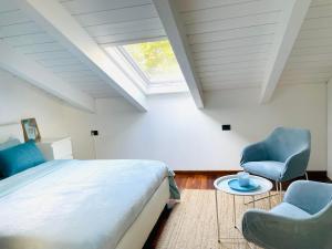 a bedroom with a bed and two chairs and a window at La finestra sul lago in Malgrate