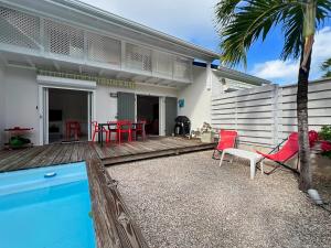 Saint MartinにあるMango Rouge, 2 bedrooms & poolの赤い椅子とプールのあるデッキのある家