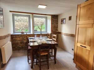 ein Esszimmer mit Tisch und Stühlen und zwei Fenstern in der Unterkunft Maison au pied des montagnes ariégeoises in Quié + 16 Fotos