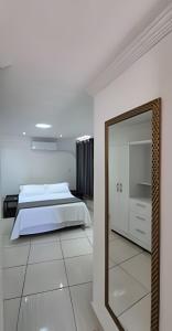 una camera da letto con un letto e uno specchio di Flat beira-mar em Natal a Natal