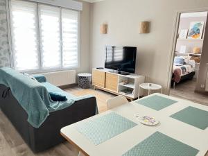 a living room with a couch and a tv at La Falaisienne - Appartement pour 4 au cœur de Falaise - "Larès" in Falaise