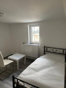 a bedroom with a bed and a chair and a window at Siegbacher Privatzimmer in Eisemroth +5 photos