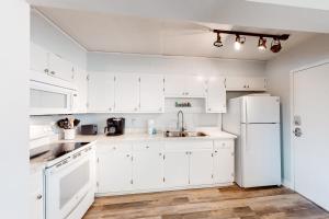 Una cocina con gabinetes blancos y un refrigerador blanco. en Sea Palms 5C, en Fort Walton Beach
