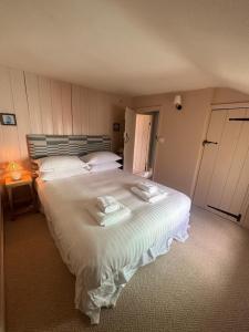 a bedroom with a large bed with two towels on it at Pilots House Aldeburgh in Aldeburgh