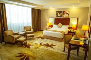 Habitación de hotel con 1 dormitorio con 1 cama y sillas en Jupiter International Hotel - Cazanchis en Addis Abeba