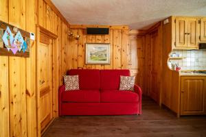 a red couch in a room with wooden walls at Le Mayen in Valtournenche