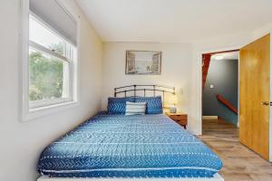 a bedroom with a bed with blue sheets and a window at Long Sands Escape in York