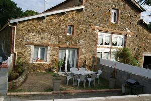 una casa de ladrillo con una mesa y sillas delante de ella en Gite du coudray 85, en Saint-André-Goule-dʼOie