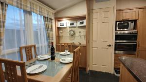 a kitchen with a table with a bottle of wine at Cosy Caravan Ty Newydd in Brynteg