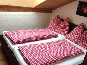 a bed with red and white checkered pillows on it at Appartement Kitzbühel mit Dachterrasse in Kitzbühel