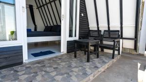 a porch with two chairs and a table and a bed at BEACH Resort - Bungalow at Beach - Gili Trawangan in Gili Trawangan