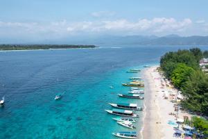a group of boats in the water on a beach at BEACH Resort - Bungalow at Beach - Gili Trawangan in Gili Trawangan